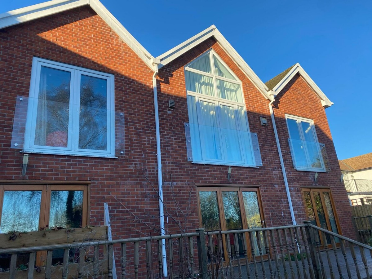 A glass Juliet balcony balustrade across a set of doors on an upper floor